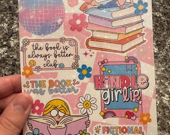 Pode incluir: Uma folha de adesivos rosa e branca com várias ilustrações e texto. Os desenhos incluem uma bola de discoteca, flores, uma menina lendo e as frases "the book is always better club", "the book was better", "Kindle Girlie" e "fictional boyfriends are better".
