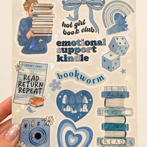 May include: A sticker sheet featuring various blue-themed illustrations including a person holding a stack of books, a bow, a rainbow, dice, a library card with the text READ RETURN REPEAT, a camera, hearts, and a stack of books labelled Let's STAY HOME and READ.
