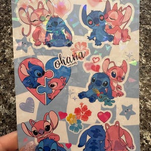 May include: A set of nine stickers featuring the characters Stitch and Angel from the Disney movie Lilo & Stitch. The stickers are on a holographic background with hearts, stars, and flowers. The text "ohana means family" is written on one of the stickers.