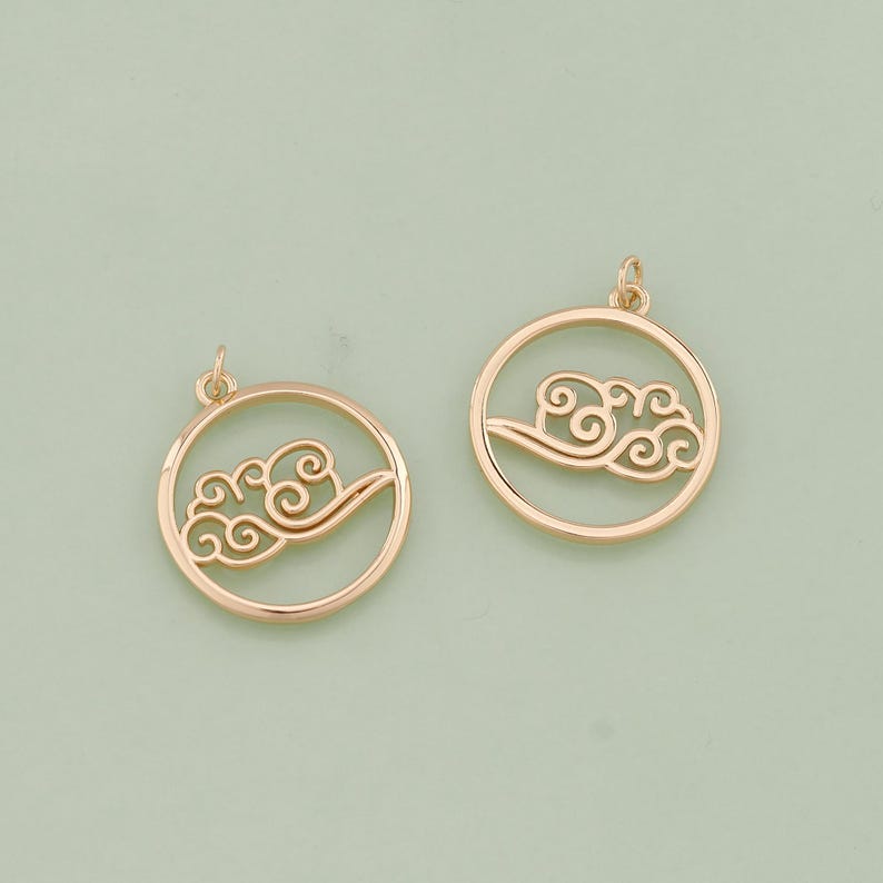 May include: Two gold-tone metal charms in the shape of a circle with a cutout design of a cloud.