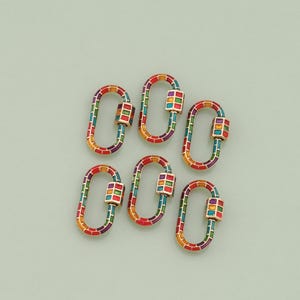 May include: Six colorful oval-shaped clasps with a square-shaped design in the center. The clasps are made of metal and have a gold finish. The square design is made of colorful enamel.