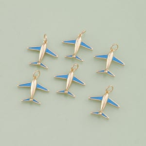 Peut inclure: Six breloques d'avion dorées avec des accents en émail bleu. Les breloques sont parfaites pour ajouter une touche de fantaisie aux bijoux ou aux objets artisanaux.