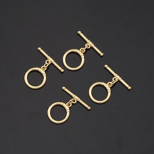 May include: Four gold-toned metal toggle clasps with a round ring and a bar. The clasps are ideal for jewelry making or other craft projects.