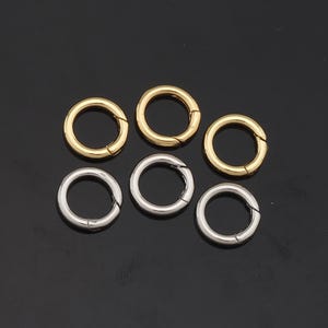 May include: Six metal rings, three gold and three silver, with a spring-loaded clasp. The rings are all the same size and are arranged in a circle.