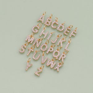 May include: A set of 26 gold-tone alphabet charms, each letter is encrusted with clear rhinestones. The charms are perfect for adding a personalized touch to jewelry.