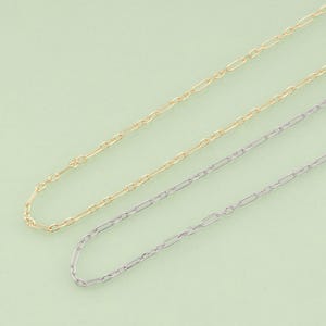 May include: Three delicate necklaces with a chain link design are displayed against a light green background. One is gold-toned, and the other two are silver-toned. The chains are thin and elegant, suitable for layering or wearing alone.
