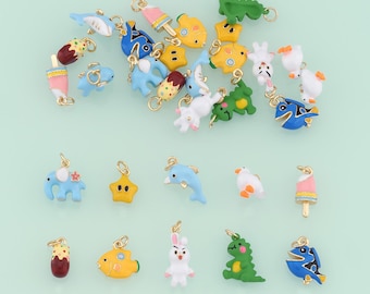 May include: Assortment of colorful enamel charms featuring various animal and food designs. The charms are made of metal and have a gold finish. The charms include a dolphin, a fish, a star, a rabbit, a dinosaur, a popsicle, an elephant, a bird, a tree, and a fish.