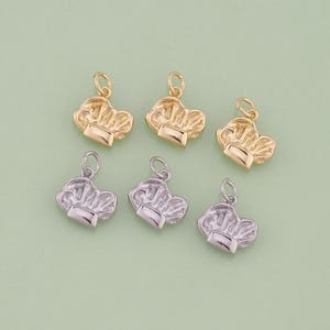 May include: Six chef hat charms in gold and silver tones. The charms are small, detailed, and have a loop at the top for attaching to jewelry. The chef hat design is a classic symbol of culinary arts.