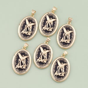 Puede incluir: Seis colgantes ovalados de color dorado con esmalte negro y un diseño en relieve de una figura alada. Los colgantes tienen un bucle en la parte superior para sujetarlos a una cadena.