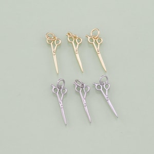 May include: Six gold and silver scissor charms. The charms are in the shape of scissors with a loop at the top for attaching to a necklace or bracelet.