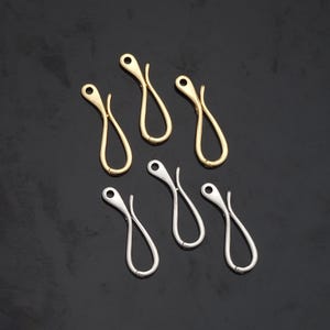 May include: Six gold and six silver metal key chain hooks. The hooks are shaped like a loop with a small opening at the top.