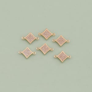May include: Six gold-tone diamond-shaped connector charms with clear crystal accents. Each charm has two small loops for attaching to jewelry.