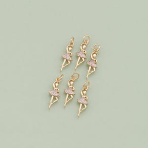 May include: Six gold-tone ballerina charms with clear rhinestone accents. The charms are perfect for jewelry making or adding a touch of sparkle to crafts.