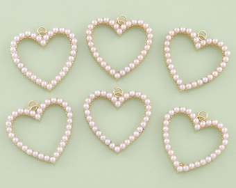 May include: Six heart-shaped charms with a gold-tone outline and filled with small, round, off-white pearls. Each charm has a small loop at the top for hanging. The charms are arranged on a light green background.