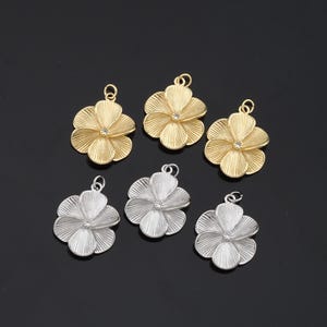 May include: Six flower-shaped charms with a clear rhinestone in the center. Three charms are gold and three are silver.