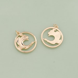 May include: Two gold-toned metal charms, one with a wave design and the other with a simple circle shape. Both charms have a loop for attaching to a necklace or bracelet.