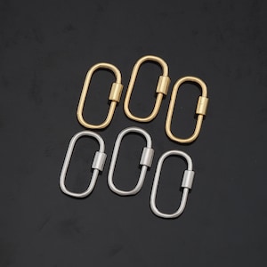 May include: Six oval-shaped screw lock carabiner clasps. Three are gold-colored, and three are silver-colored. The clasps are arranged in two rows of three against a black background. The clasps are made of metal and have a screw mechanism for secure closure.