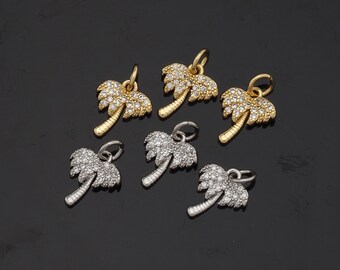 May include: Six palm tree charms with clear rhinestones. Three charms are gold and three are silver.