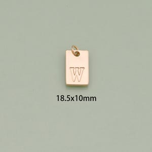 K&ouml;nnte beinhalten: Goldfarbener Metallanh&auml;nger mit dem Buchstaben "W" auf einem rechteckigen Anh&auml;nger graviert. Der Anh&auml;nger misst 18,5 x 10 mm.