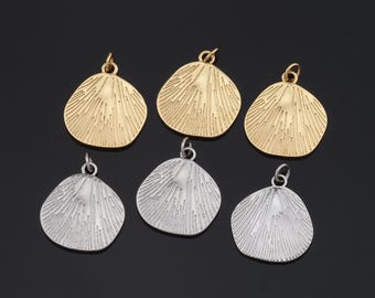 May include: Six metal pendants in two finishes: gold and silver. Each pendant is shaped like a scallop shell with a textured surface.