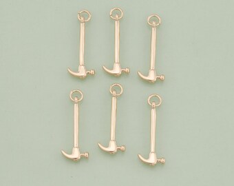 May include: Six gold-colored hammer charms with a loop at the top. The charms are about 1 inch long.
