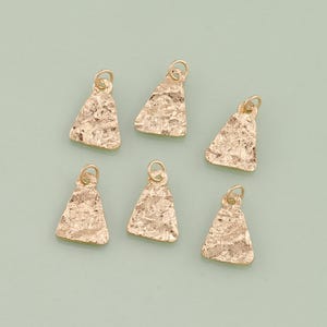 May include: Six gold-toned triangle-shaped charms with a textured surface. The charms have a loop at the top for attaching to jewelry.