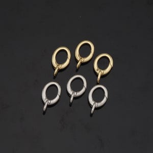 May include: Six oval-shaped metal clasps, three gold and three silver, with a spring-loaded closure. These clasps are ideal for attaching jewelry, charms, or other accessories.