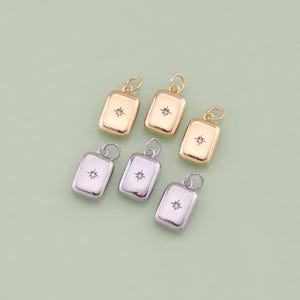 May include: Five gold and silver charms with a small star-shaped rhinestone in the centre. The charms are rectangular and have a loop at the top for attaching to a necklace or bracelet.