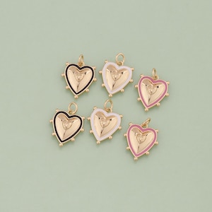May include: Six gold heart-shaped charms with different colored enamel borders. The charms have a raised heart design in the center. The colors are black, white, pink, and red.