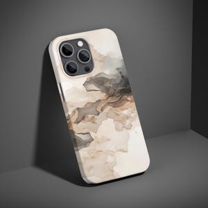 Puede incluir: Una funda para smartphone con una base color crema y un diseño de acuarela en tonos marrones y grises. La funda tiene un acabado brillante y un recorte para la cámara. El diseño se asemeja a nubes o humo abstractos.