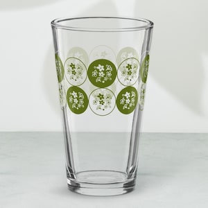 以下が含まれることがあります： 緑と白の花柄の透明なガラス製の飲みグラス。パターンは、緑色の背景に白い花が描かれた円形です。