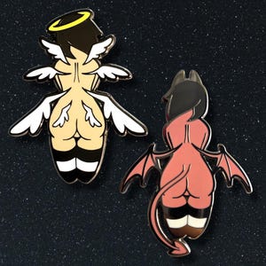 May include: Two enamel pins, one depicting an angel with a halo and white wings, the other a devil with horns and red wings. Both pins feature a stylized human form with black and tan details.
