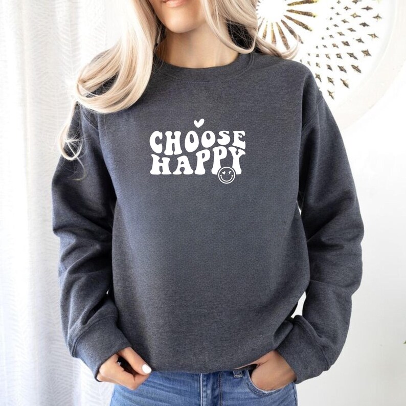 May include: A dark gray sweatshirt with the text "CHOOSE HAPPY" in white, featuring a retro font and a smiley face.