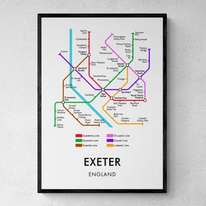 May include: A framed print showing a detailed map of Exeter, England, with colored lines indicating different routes and stations. The city's name and 'England' are printed at the bottom. The map is set against a white background.