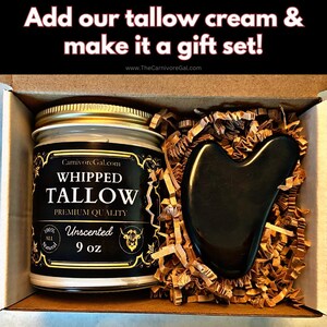 May include: A gift set containing a 9 ounce jar of unscented whipped tallow cream and a black gua sha tool. The jar has a gold lid and a black and gold label that reads "CarnivoreGal.com WHIPPED TALLOW PREMIUM QUALITY 100% ALL NATURAL Unscented 9 oz".