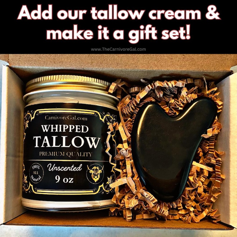 May include: A gift set containing a 9 ounce jar of unscented whipped tallow cream and a black gua sha tool. The jar has a gold lid and a black and gold label that reads "CarnivoreGal.com WHIPPED TALLOW PREMIUM QUALITY 100% ALL NATURAL Unscented 9 oz".