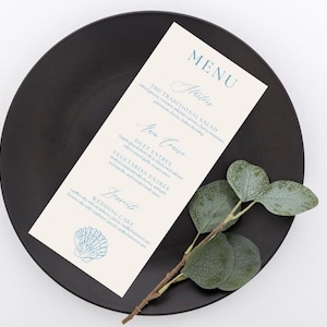 Pode incluir: Um menu de casamento com texto azul e um gráfico de concha, colocado em um prato preto com um ramo de vegetação. O menu inclui seções para entradas, prato principal e sobremesas.