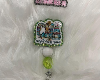 May include: A green, white, and blue glitter badge reel with a "CNA Certified Nursing Assistant" design. The reel is attached to a white and green beaded chain with a silver clip.