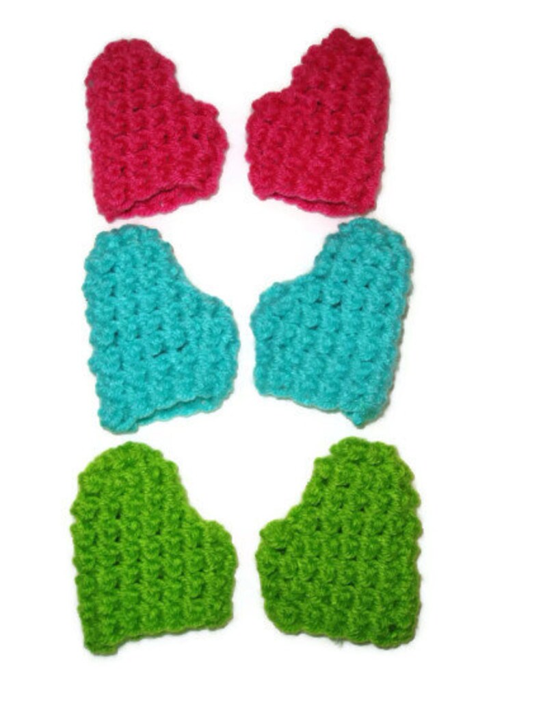 K&ouml;nnte beinhalten: Sechs geh&auml;kelte fingerlose Handschuhe in Herzform in Pink, T&uuml;rkis und Gr&uuml;n.