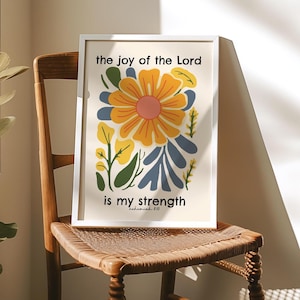 May include: A white framed print with a floral design and the text "the joy of the Lord is my strength - Nehemiah 8:10".