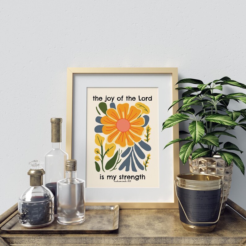 May include: A framed print with a floral design and the text "the joy of the Lord is my strength" with the scripture reference "Nehemiah 8:10".