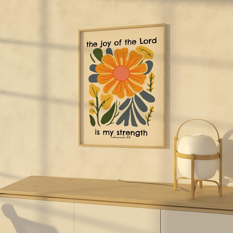 May include: A beige poster with a floral design in shades of yellow, orange, and blue. The text "the joy of the Lord is my strength" is printed on the poster, with the scripture reference "Nehemiah 8:10" below.