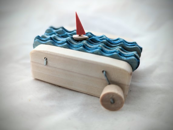 A hand-crafted wooden sailboat that rocks and sways with mesmerizing kinetic motion — desk art that actually *moves*.