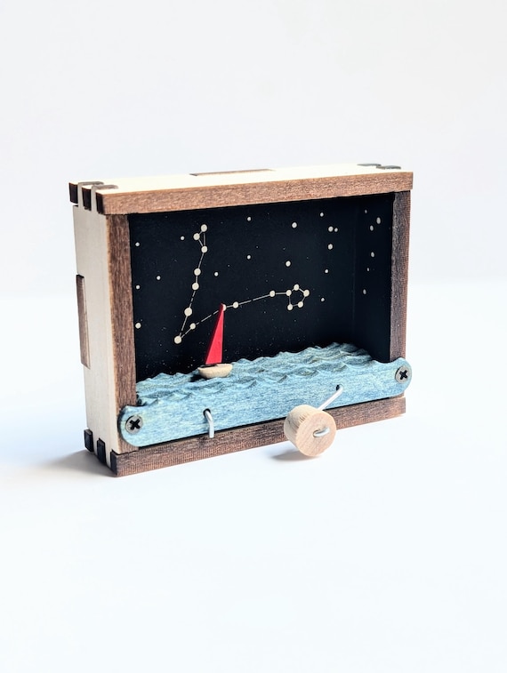 A tiny kinetic wooden sailboat that moves — constellation-themed desk sculpture that doubles as a fidget object and a conversation piece.