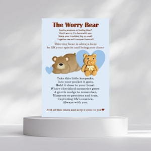 May include: A card with the text "The Worry Bear" and a poem about comfort and support. The card features illustrations of two teddy bears, one brown and one tan, with blue heart accents. The card is displayed on a white pedestal.