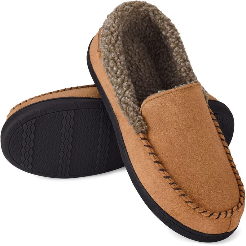 Puede incluir: Un par de zapatillas marrones de ante con un forro interior suave y afelpado. Las zapatillas tienen una suela negra y costuras decorativas en los bordes. El dise&ntilde;o es de tipo slip-on, perfecto para uso en interiores.
