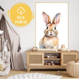 May include: Watercolor print of a bunny with long ears and a light brown and white coat. The artwork is framed and labeled "DIGITAL DOWNLOAD" in a yellow circle. The print is displayed in a child's room.