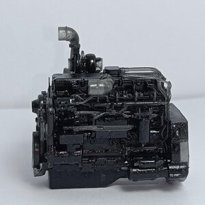 May include: A detailed, black engine model with intricate components, including pipes and various mechanical parts. The engine is set against a plain white background, highlighting its complex design and structure. The model appears to be a miniature replica.