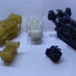 Puede incluir: Una colección de cinco modelos de motores en miniatura de diversos tamaños y colores. Dos son de color amarillo translúcido, uno es blanco opaco y dos son de color negro mate. Cada modelo presenta detalles mecánicos intrincados, incluyendo cilindros y bloques de motor.