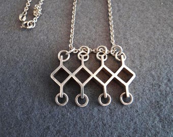 Peut inclure: Un collier en argent avec un pendentif géométrique présentant un motif de diamant répété. Le pendentif est suspendu à une chaîne en argent.